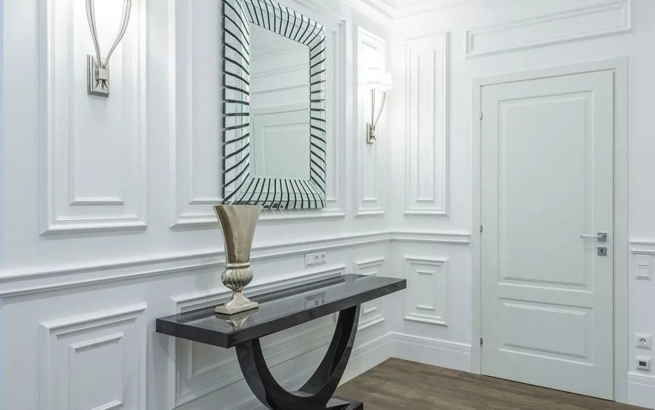 Entrée étroite éclairée par deux appliques et un mur du fond peint en prune